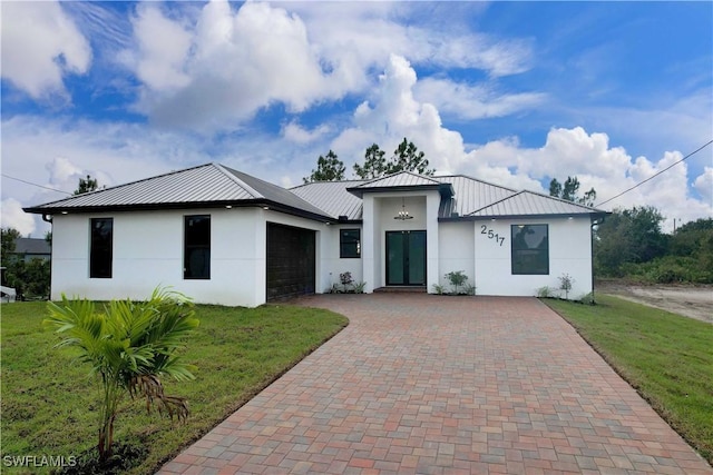 2517 11th St SW, Lehigh Acres, FL 33976 - view of front of property with a standing seam roof, stucco siding, decorative driveway, and a garage
