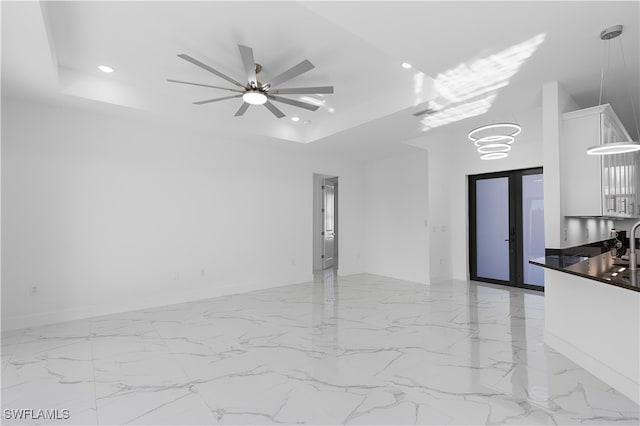 unfurnished room featuring a tray ceiling, french doors, and ceiling fan with notable chandelier