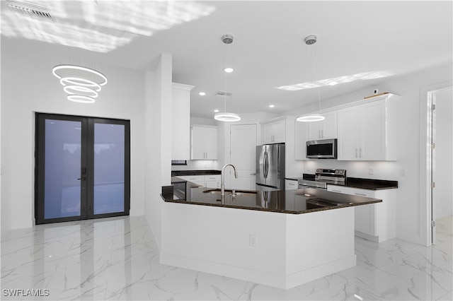 kitchen featuring appliances with stainless steel finishes, a kitchen island with sink, sink, pendant lighting, and white cabinets