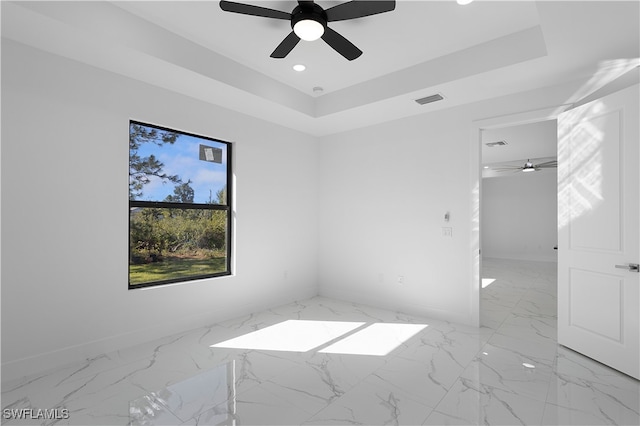 spare room with ceiling fan and a tray ceiling