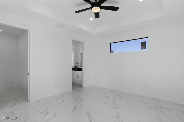 2517 11th St SW, Lehigh Acres, FL 33976 - unfurnished bedroom with light marble finish flooring, recessed lighting, a raised ceiling, baseboards, and ensuite bath