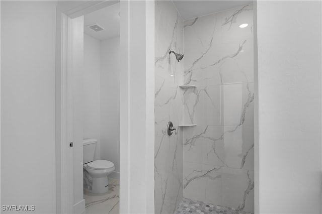 bathroom with a tile shower and toilet