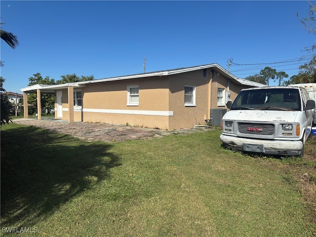 view of home's exterior with central AC, a yard, and a carport