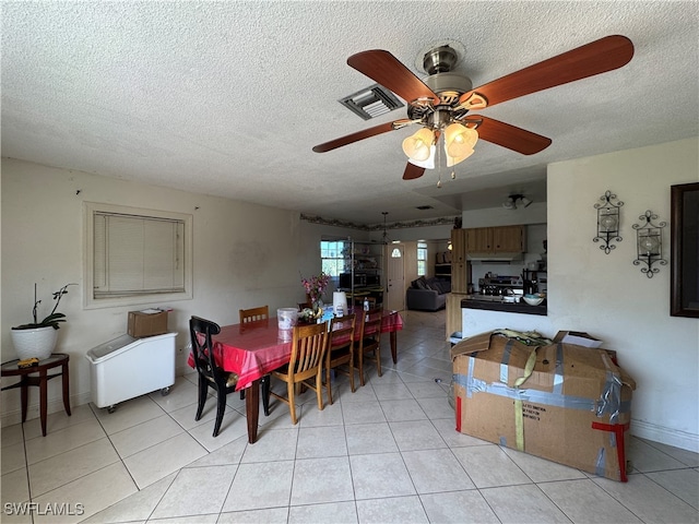 dining space featuring ceiling fan, light tile patterned flooring, and a textured ceiling