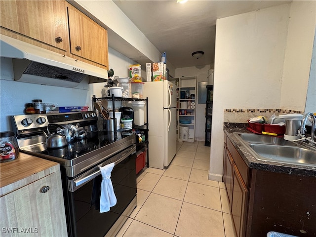 kitchen featuring light tile patterned flooring, white fridge, stainless steel electric range oven, and sink