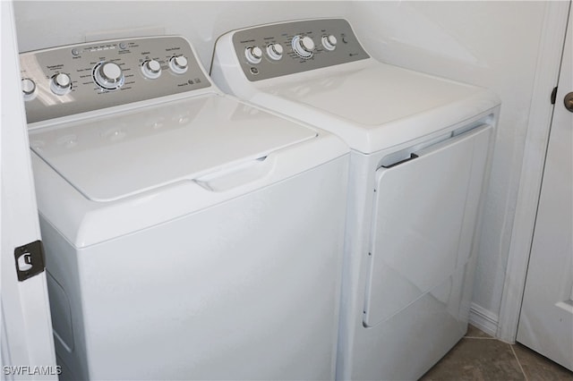 laundry area featuring washing machine and dryer and dark tile patterned floors