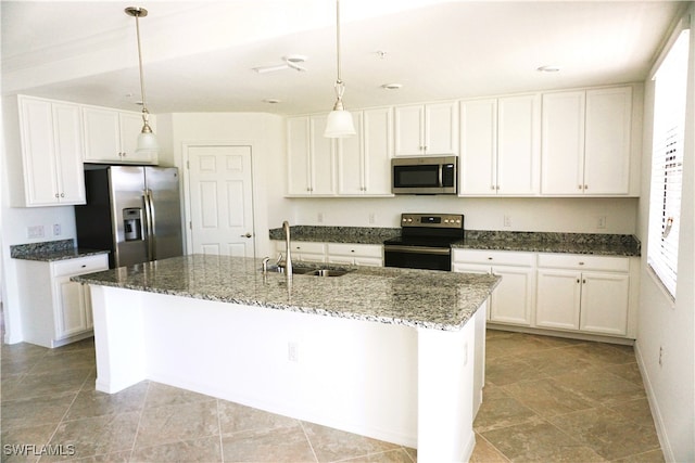 kitchen with white cabinetry, sink, dark stone countertops, a center island with sink, and appliances with stainless steel finishes