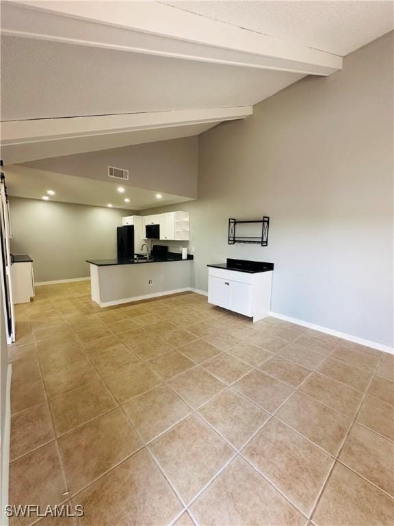 unfurnished living room featuring light tile patterned floors and vaulted ceiling with beams