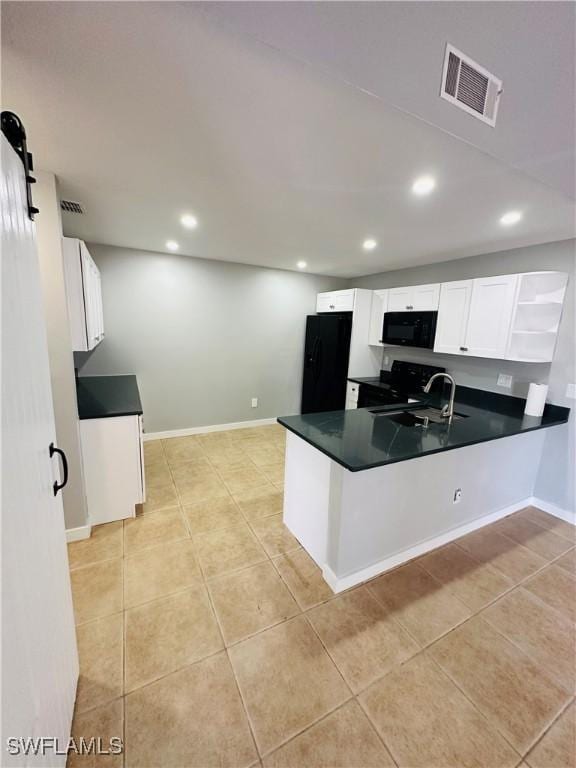 kitchen featuring white cabinetry, a barn door, kitchen peninsula, and black appliances