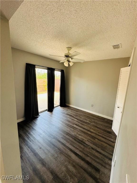 empty room featuring a textured ceiling, ceiling fan, and dark hardwood / wood-style floors