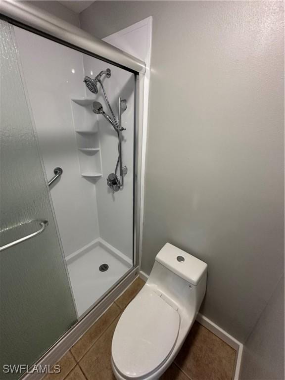 bathroom with toilet, tile patterned flooring, and walk in shower