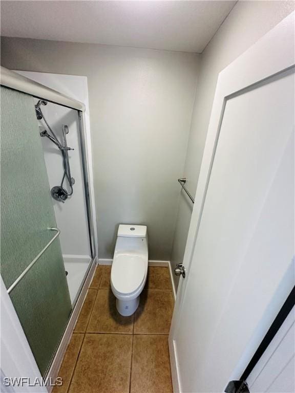 bathroom featuring toilet, a shower with door, and tile patterned flooring