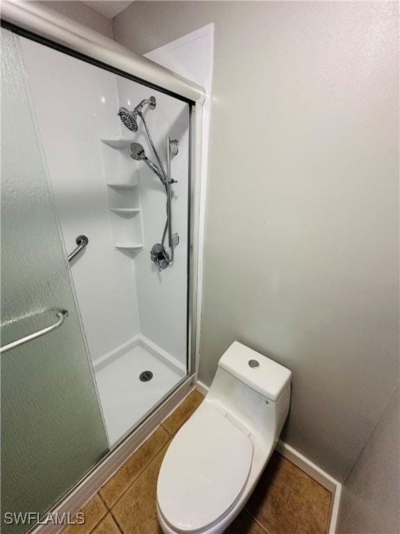 bathroom with tile patterned floors, toilet, and walk in shower