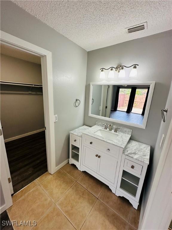 bathroom with a textured ceiling, tile patterned flooring, and vanity