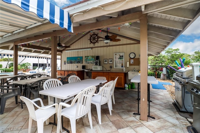 view of patio with ceiling fan and an outdoor bar