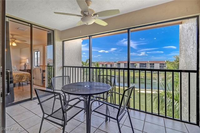 sunroom / solarium with ceiling fan, a water view, and a healthy amount of sunlight