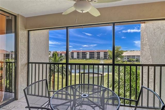 unfurnished sunroom with ceiling fan and a water view