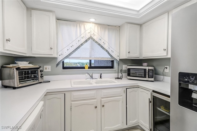 kitchen with appliances with stainless steel finishes, white cabinets, sink, and wine cooler