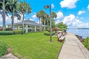 view of property's community with a lawn and a water view