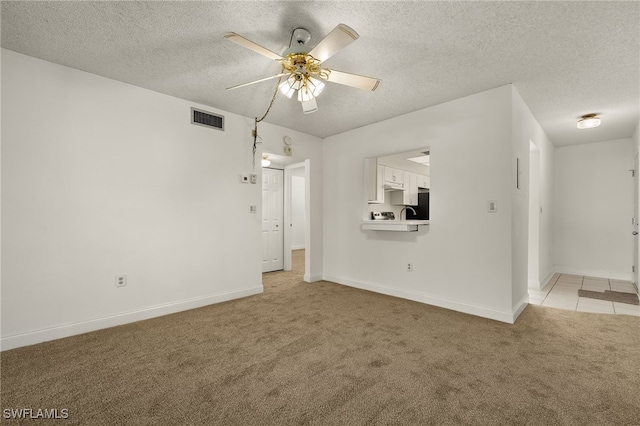 unfurnished living room with ceiling fan, a textured ceiling, and light carpet