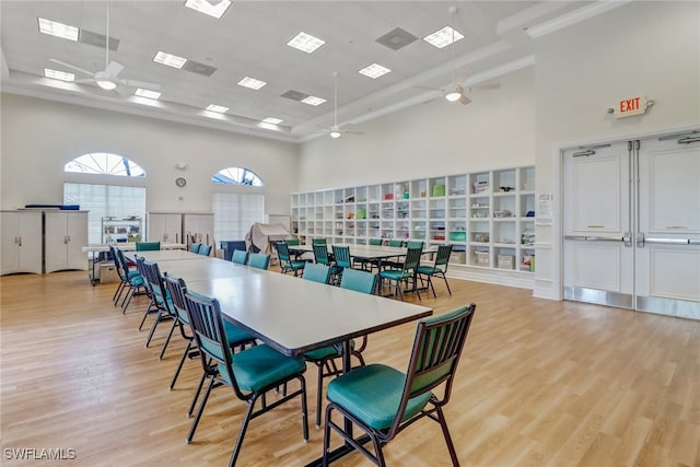 dining room featuring ceiling fan, light wood-type flooring, and a high ceiling