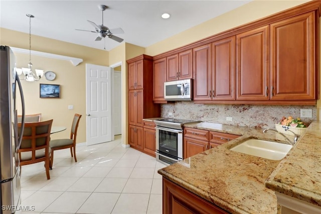 kitchen with pendant lighting, sink, decorative backsplash, light stone countertops, and appliances with stainless steel finishes