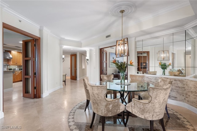 dining space with crown molding and decorative columns