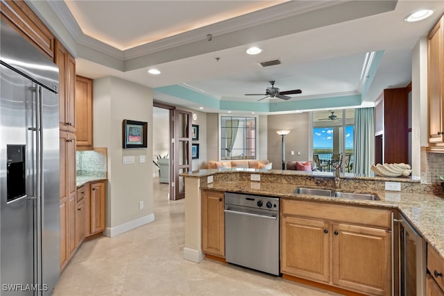 285 Grande Way Unit 705, Naples, FL 34110 - kitchen with stainless steel appliances, a raised ceiling, a peninsula, backsplash, and ceiling fan