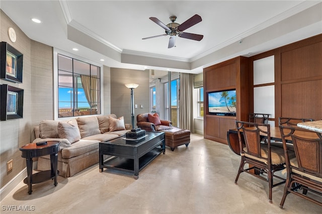 living room with a tray ceiling, ceiling fan, and crown molding