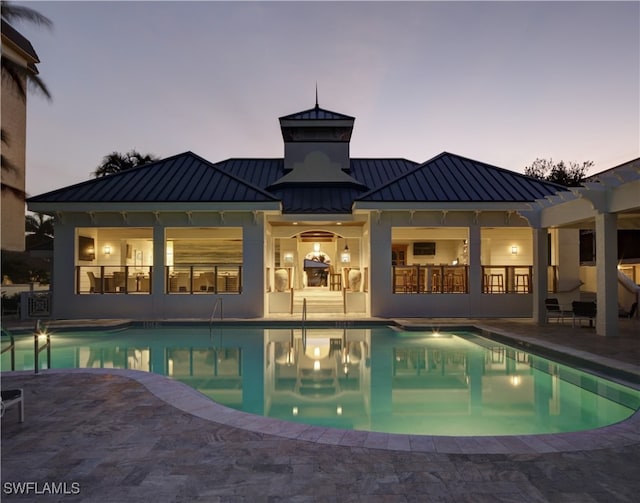 pool at dusk with a patio area