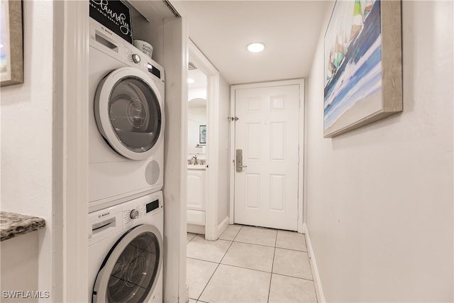 laundry area with stacked washer / drying machine and light tile patterned flooring