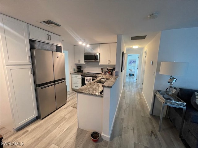 kitchen featuring white cabinets, stone countertops, light hardwood / wood-style floors, kitchen peninsula, and stainless steel appliances