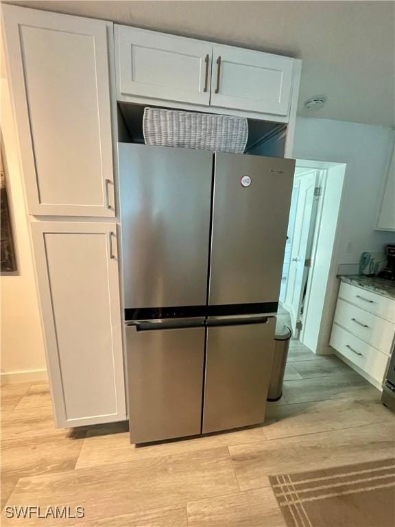 kitchen featuring stainless steel fridge, light hardwood / wood-style floors, and white cabinetry