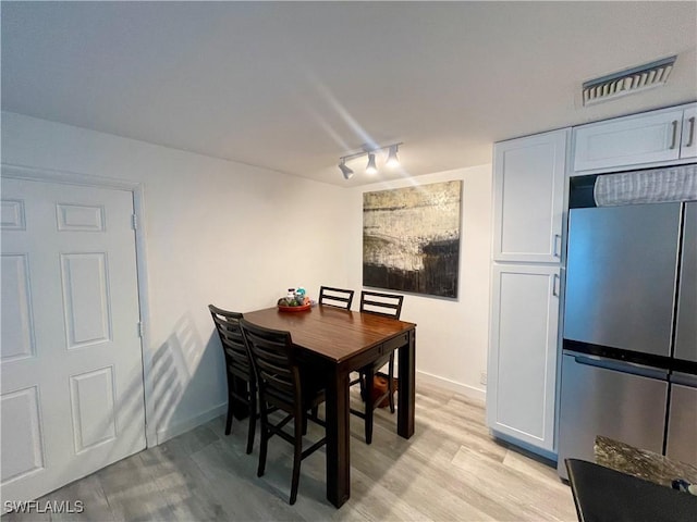 dining area with track lighting and light hardwood / wood-style flooring