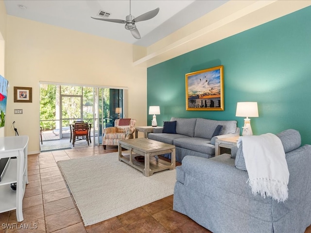 living room featuring tile patterned flooring, ceiling fan, and a high ceiling