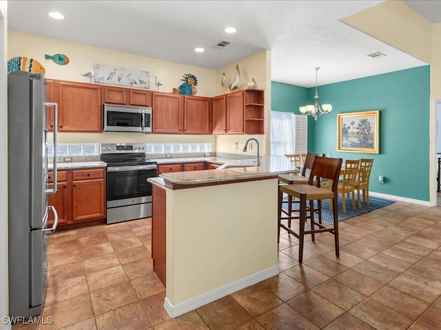 kitchen with sink, an inviting chandelier, kitchen peninsula, decorative light fixtures, and appliances with stainless steel finishes