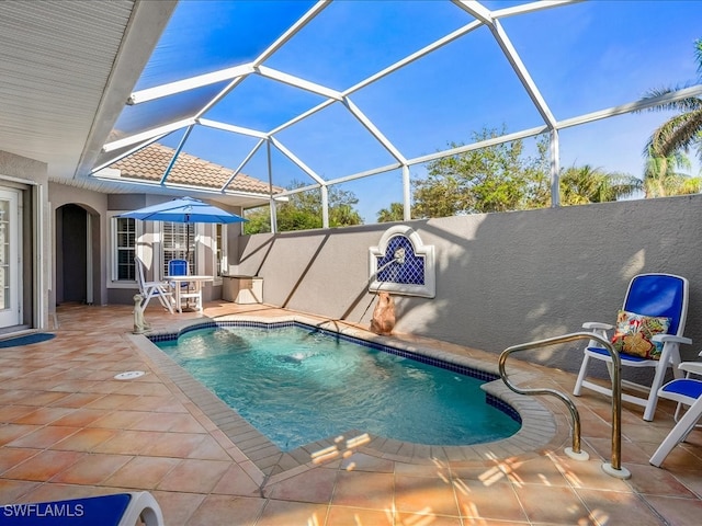 view of swimming pool featuring pool water feature, glass enclosure, and a patio area