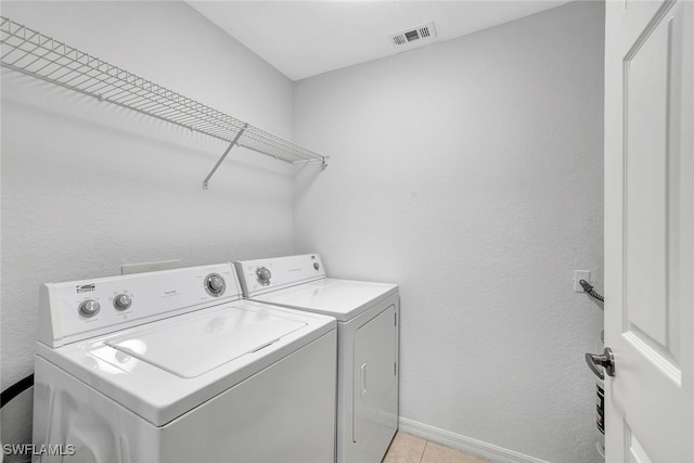 laundry area with light tile patterned floors and washer and dryer