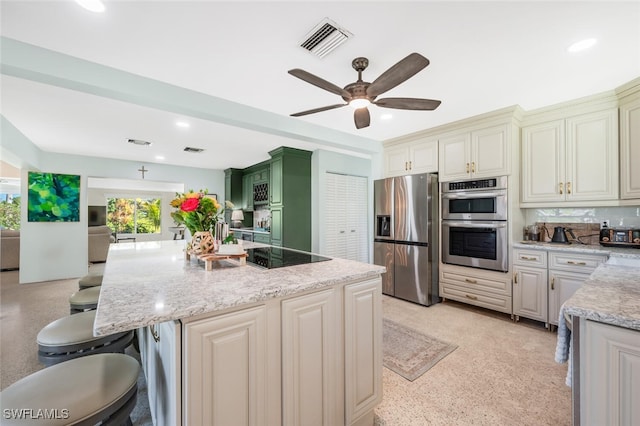 kitchen with stainless steel appliances, light stone countertops, a breakfast bar area, and a center island with sink