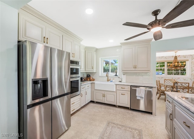 kitchen featuring sink, ceiling fan, appliances with stainless steel finishes, tasteful backsplash, and light stone countertops