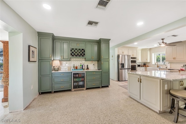 kitchen with a breakfast bar, stainless steel appliances, wine cooler, tasteful backsplash, and light stone countertops