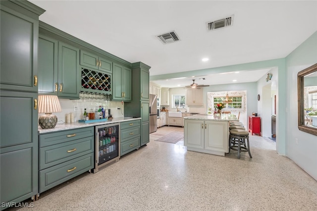 kitchen featuring wine cooler, plenty of natural light, a kitchen breakfast bar, green cabinets, and a kitchen island