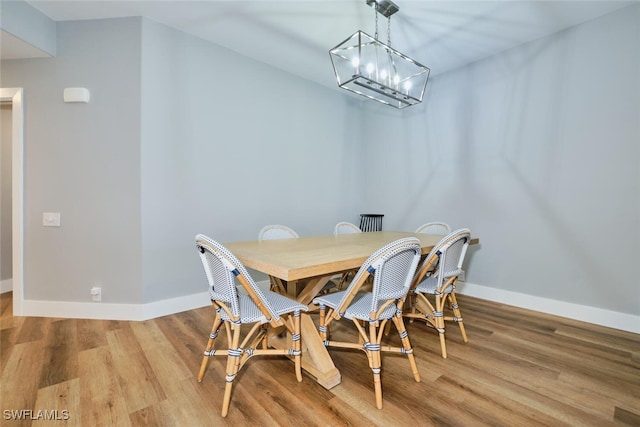 dining area featuring wood-type flooring and an inviting chandelier