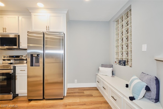 kitchen with white cabinets, appliances with stainless steel finishes, and light hardwood / wood-style floors