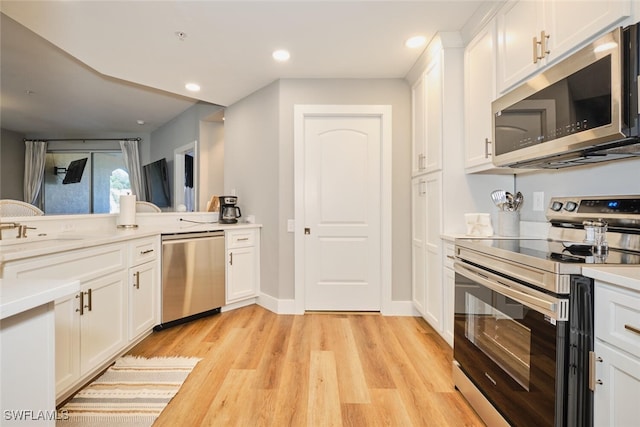 kitchen with appliances with stainless steel finishes, light hardwood / wood-style flooring, and white cabinetry