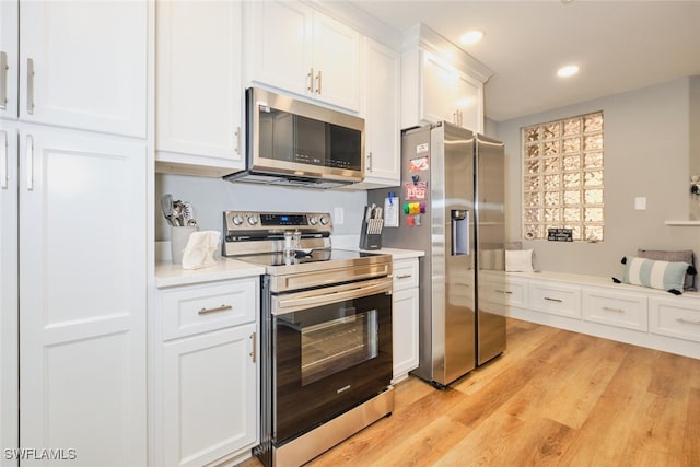 kitchen with white cabinets, light wood-type flooring, and appliances with stainless steel finishes