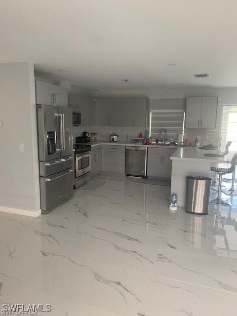 kitchen with gray cabinetry, decorative backsplash, sink, and stainless steel appliances