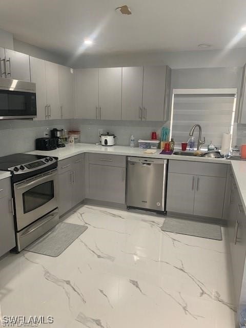 kitchen featuring gray cabinets, sink, and stainless steel appliances