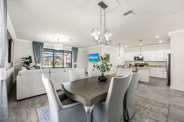 dining area with light wood-type flooring, an inviting chandelier, and ornamental molding