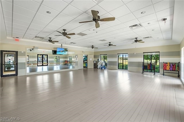 workout area with a paneled ceiling and light wood-type flooring